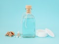 Face tonic or makeup remover in a glass bottle, cotton pads, wooden cotton buds and sea shells on pastel blue background. Hygiene Royalty Free Stock Photo