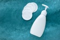 Face tonic in white dispenser bottle and many cotton discs on aqua background. Plastic bottle with liquid. Text, copy space. Royalty Free Stock Photo