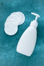 Face tonic in white plastic dispenser bottle and cotton pads on turquoise background. Make-up remover, skin care concept Royalty Free Stock Photo