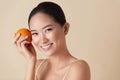 Face. Woman And Fruit Beauty Portrait. Smiling Asian Model With Orange Looking At Camera Against Beige Background. Royalty Free Stock Photo