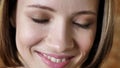 Face of young attractive shy girl is smiling, watching at camera, brick background