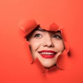 The face of a young beautiful girl with a bright make-up and with plump red lips peeks into a hole in orange paper Royalty Free Stock Photo