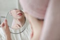 face of young beautiful healthy woman and reflection in the mirror. Young woman with a towel on head apply cream on face Royalty Free Stock Photo