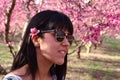 Face of young beautiful woman with pink flowers peach tree in her hair Royalty Free Stock Photo