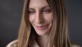 Face of young charming shy girl is watching at camera, smiling, grey background