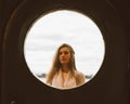 The Face Of Young Girl In Round Frame Window On Background Of Sea, Ocean, On Waterfront. Portrait In Circle, Backlit