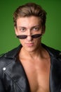 Face of young handsome rebellious man wearing leather jacket and sunglasses Royalty Free Stock Photo