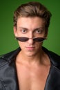 Face of young handsome rebellious man wearing leather jacket and sunglasses Royalty Free Stock Photo