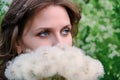 Face of a young woman in close-up with a bouquet of dandelions