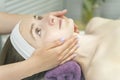 Face of young woman during procedure of applying cream. Healthy facial massage, lymphatic drainage massage. Side view