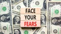 Face your fears and support symbol. Concept words Face your fears on wooden blocks on dollar bills. Beautiful background from
