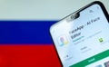 FaceApp app on the screen of smartphone with the flag of Russia at the blurred background behind it.