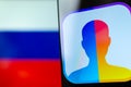 FaceApp logo on the screen of smartphone with the flag of Russia at the blurred background behind it.
