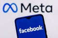 Facebook changes its name to Meta. Smartphone with Facebook logo on the background of Meta logo