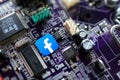 Facebook icon on computer motherboard close-up, social media and technology concept