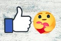 Facebook new Care Empathetic Emoji Reaction and Facebook Like on wooden background Royalty Free Stock Photo