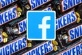 Facebook paper logo on many Snickers chocolate covered wafer bars in brown wrapping. Advertising chocolate product in Facebook