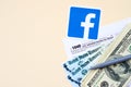 Facebook printed logo lies with 1040 Individual Income tax return form with Refund Check and hundred dollar bills on beige