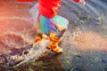 Girl in gumboots splashing spring puddle Royalty Free Stock Photo