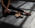 Faceless ballerina sits on the floor and puts on pointe shoes.