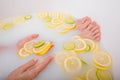 Faceless beautiful young woman takes a bath with milk lemons and lime. Cropped photo. Close-up of female hands and feet Royalty Free Stock Photo