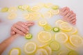 Faceless beautiful young woman takes a bath with milk lemons and lime. Cropped photo. Close-up of female hands and feet Royalty Free Stock Photo