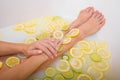 Faceless beautiful young woman takes a bath with milk lemons and lime. Cropped photo. Close-up of female hands and feet Royalty Free Stock Photo