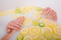 Faceless beautiful young woman takes a bath with milk lemons and lime. Cropped photo. Close-up of female hands and feet Royalty Free Stock Photo