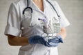 A faceless doctor puts a blister of pills in a mini shopping cart.