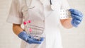 A faceless doctor puts a blister of pills in a mini shopping cart.