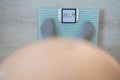 Faceless fat woman measures weight on a bathroom scale. Top view of a large naked female belly and feet in gray socks on Royalty Free Stock Photo