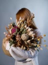 Faceless girl holds a bouquet of dried flowers