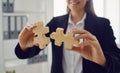 Faceless hands of a businesswoman with wooden puzzles in hands in the office.