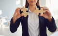 Faceless hands of a businesswoman with wooden puzzles in hands in the office.