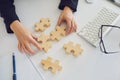 Faceless hands of a businesswoman with wooden puzzles on a white table in the office.