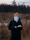 Faceless killer. Dangerous man with a white cloth on his face and a knife in his hand on the reeds in the evening. Halloween Royalty Free Stock Photo