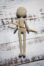 Faceless knitted human figure with knitting needle on wooden background