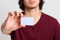 Faceless male stretches hand with blank card for your advertisement or promotion text, poses at white background, man wearing