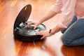 Faceless middle section of young woman emptying the deposit of an automatic vacuum cleaner to clean the floor, opened machine hous