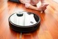 Faceless middle section of young woman using automatic vacuum cleaner to clean the floor, controlling smart machine housework robo