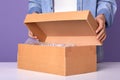 Faceless portrait of young man wearing denim shier and white shier opens brown carton box with present for his birthday, gift in Royalty Free Stock Photo