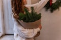 Faceless portrait of young woman in white knitted sweater, holding in hands Christmas bouquet Royalty Free Stock Photo