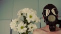 A faceless shirtless man in a gas mask with flowers. An unrecognizable man with a naked torso in a black gas mask with a