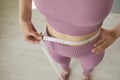 Faceless slim sporty woman in sportswear measure waist with measuring tape. Royalty Free Stock Photo