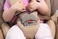 Faceless small baby sitting in special car seat with safety seatbelts