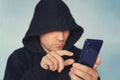 Faceless unrecognizable hooded person using mobile phone, identity theft and technology crime concept, selective focus on body, ha Royalty Free Stock Photo
