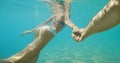 Faceless woman with beautiful body in bikini swimming underwater, holding boyfriend hand