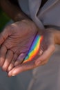 Faceless woman catching rainbow ray with her hands outdoors.