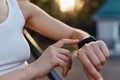 Faceless woman checking fitness and health tracking wearable device on her hand, unknown female in white top posing outdoor in