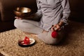 Faceless woman meditates at home on carpet and plays on copper singing bowl. Sound therapy, recreation, meditation